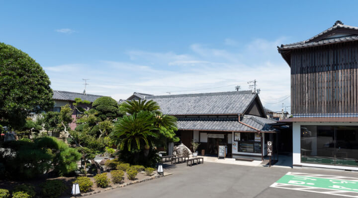 青空の下、日本庭園の庭と築百五十年の古民家を改装した店の外観